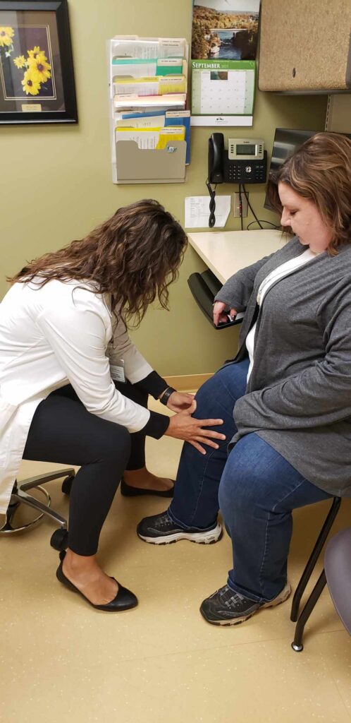 377145861_1130758181234346_669871578067454918_n Healthcare professional examining a patient’s knee in a clinical setting, emphasizing personalized care and support for health issues.