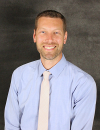 John Kampa, MD, orthopedic surgeon at Burnett Medical Center, smiling in professional attire with a light blue shirt and pink tie.