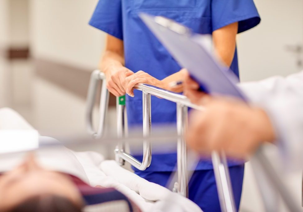 profession, people, healthcare, reanimation and medicine concept - medics or doctors carrying unconscious woman patient on hospital gurney to emergency room