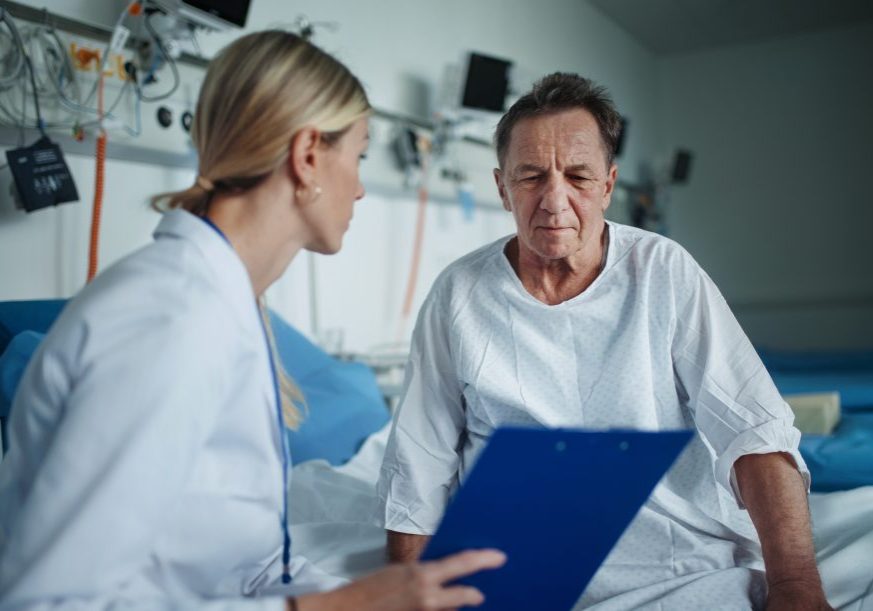 Young woman doctor explaining diagnosis to her patient in hospital room.