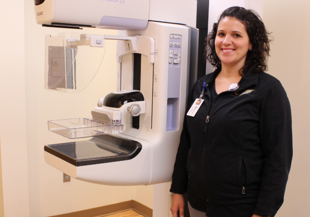 Healthcare professional standing next to a Selenia Dimensions mammography machine, emphasizing the importance of breast cancer screening and early detection at Burnett Medical Center.